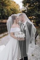 A bride and groom are kissing under a veil photo