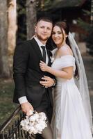 A bride and groom are posing for a picture in front of a fence photo