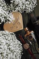 A heart-shaped card with the words written on it sits on a table with a bottle of perfume and a watch photo