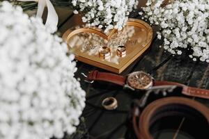 A heart-shaped box with two rings inside and a watch on top. Concept of love and commitment photo