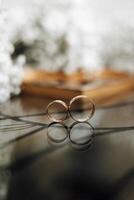 Two gold wedding rings are placed on a table. The rings are reflecting the light and creating a beautiful, romantic atmosphere photo