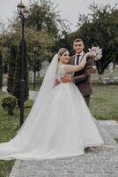 A bride and groom are posing for a picture in a park photo