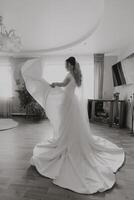 A woman in a white dress is standing in a room with a large mirror photo