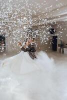 A bride and groom are dancing in the air with confetti falling around them photo