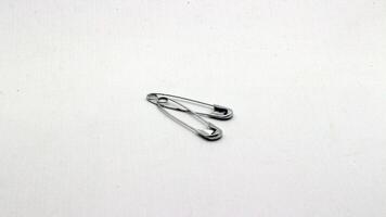 The safety pin is made of metal and silver in color. photo