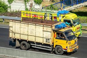 Two Mitsubishi Canter trucks racing fast on the toll road is very dangerous and violates the speed limit regulations, Indonesia, 16 July 2024. photo