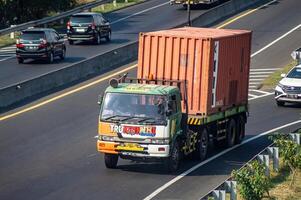 a trailer truck or container truck passing on the Surabaya Gresik toll road carrying a full load of logistics for export and import globally, Indonesia, 16 July 2024. photo
