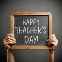 A student holds up a blackboard And 'happy Teachers day' are written in white chalk on the board in capitalized letters photo