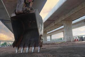 Clear excavator bucket beam Large manual construction machinery buckets Under the expressway road bridge Concept of using machinery in construction photo