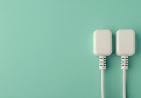 Two White Electrical Plugs on Teal Background photo