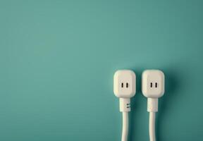 Two White Electrical Plugs on Teal Background photo