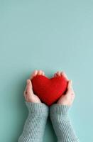 Hands Holding Red Heart on Blue Background photo