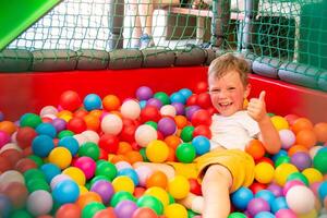 Boy playing on the playground, in the children's maze with balls. photo