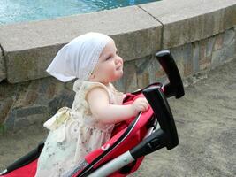 Portrait of adorable toddler girl sitting in stroller photo