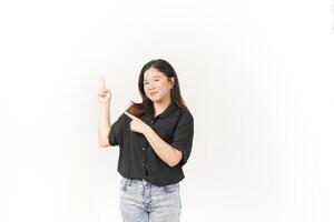 Young Asian woman presenting and pointing side copyspace wearing Black t-shirt and jeans isolated on white background photo