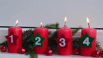Countdown Four Advent red candles with numbers burning, fir branches and Christmas zero waste decorations in windowsill. Holiday preparation. Catholic traditions of Christmas new year winter holidays video