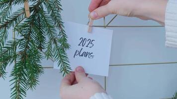 2025 PLANS text on white paper note on vision board with Christmas decor. New year aims resolutions. New me you concept visualizing dreams video