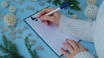 Female hands writing handwritten new year resolutions aims goals on paper notepad. Preparation for New Year. Concept of planning and setting goals for personal development video