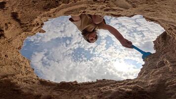 pov bottom view of a little girl digging a hole in the sand. action cam video