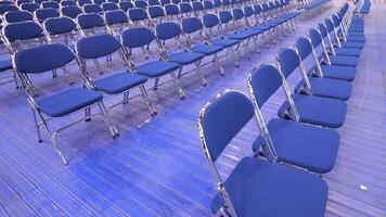 rows of empty blue chairs without spectators before seminar, concert, primaries video