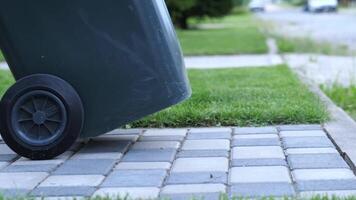 a man rolls an empty trash can from the street after garbage collection service video