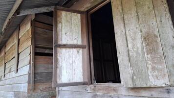 A weathered wooden window with a slightly open door peering into the unknown photo