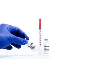 Doctor holding vaccine vial in blue gloved hand on white background. photo