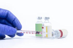 Hand in blue glove holding syringe and vials isolated on white background. photo