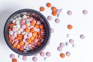Colorful pills in a round plastic container on white background. photo