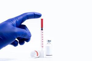 Medical vials and syringe with blue gloves on white background photo
