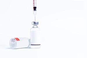 Vaccine bottle with needle sticking out of it isolated on white background. photo