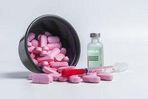 Vaccine bottle with spilled pink pills and syringe on side on white background. photo