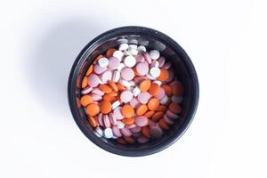 Colorful pills in a plastic container isolated on white background. photo