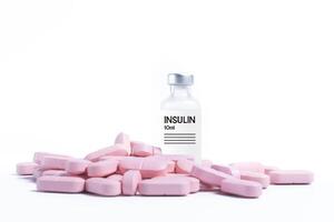 Pile of pink pills with vaccine bottle on white background photo