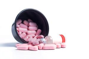 Pink pills and vaccine bottle spilled from black plastic box on white background photo