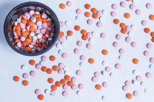 Colorful pills in a round plastic container on white background. photo