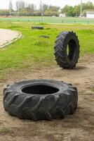 Large tractor tires set up in a sports complex for obstacle courses or CrossFit training. The rugged terrain and equipment add to the challenge and excitement of the workout. photo