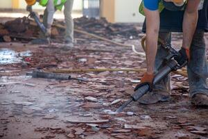 A construction worker on a renovation site using a pneumatic hammer, focused and skillful, breaking through concrete for a precise and efficient remodeling job. photo