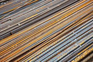 Close-up of steel rebar at a construction site. The textured bars are aligned and ready for use in reinforced concrete structures, showcasing the strength and precision of modern engineering. photo