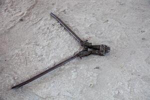 A close-up of a rebar cutter on a construction site floor, showcasing its sharp blades and rugged design, ready for heavy-duty metal cutting tasks. photo