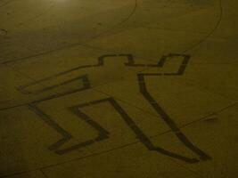 A lifeless body lies on the ground, carefully drawn in chalk. The scene is solemn, capturing the gravity of crime and investigation. Ideal for crime scene, mystery, and detective-themed visuals. photo