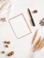 Frame from sweater, fall leaf and acorns, envelope and postcard on white background photo