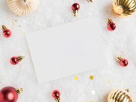 Empty white postcard and various red and gold christmas decor on artificial snow background. photo