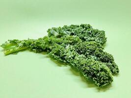 Kale leaf salad vegetable isolated on green background. Creative layout made of kale closeup. Food concept. photo