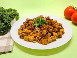 Oseng Tempe and Tofu is Indonesian stir-fried tempeh, tofu and carrot seasoned with shallots, garlic, salt, bay leaf, galangal and sweet soy sauce served on white plate photo