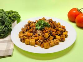 Oseng Tempe and Tofu is Indonesian stir-fried tempeh, tofu and carrot seasoned with shallots, garlic, salt, bay leaf, galangal and sweet soy sauce served on white plate photo