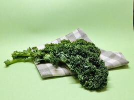 Kale leaf salad vegetable isolated on green background. Creative layout made of kale closeup. Food concept. photo