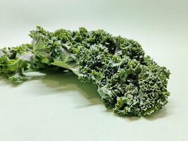 Kale leaf salad vegetable isolated on green background. Creative layout made of kale closeup. Food concept. photo