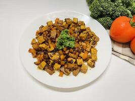 Oseng Tempe and Tofu is Indonesian stir-fried tempeh, tofu and carrot seasoned with shallots, garlic, salt, bay leaf, galangal and sweet soy sauce served on white plate photo
