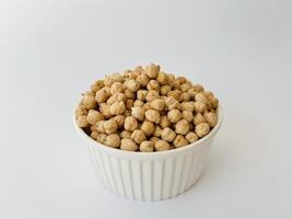 Raw dry chickpea in small ceramic bowl on white background. Traditional ingredient for cooking hummus. Middle Eastern and Mediterranean cuisine. Selected focused photo